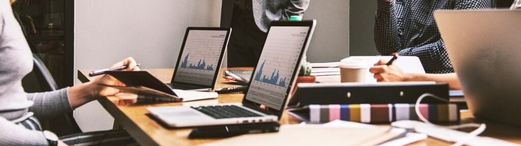 marketing team in office with laptops having a discussion.