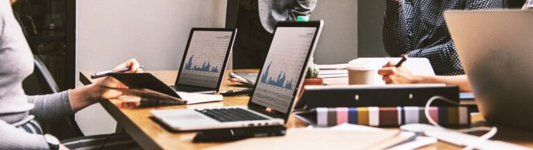 marketing team in office with laptops having a discussion.